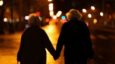 elderly couple holding hands walking at night