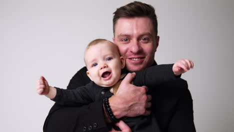 happy caucasian father with his lovely baby. man holding a child smiles to camera embracing and kissing the kid. close up.