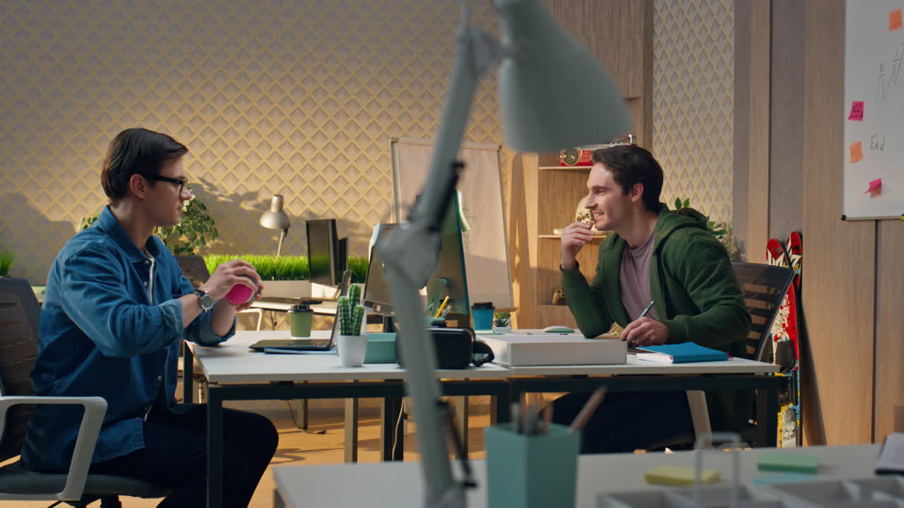 사무실에서 일하는 젊은 사업가들이 함께 소통하고 있습니다. 컴퓨터를 보는 남자