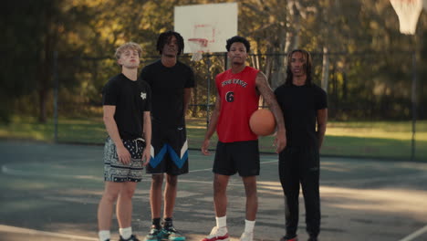 four young men posing on a basketball court