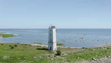 Cinematic-coastline-aerial-of-a-white-lighthouse-in-Saaremaa,-Estonia