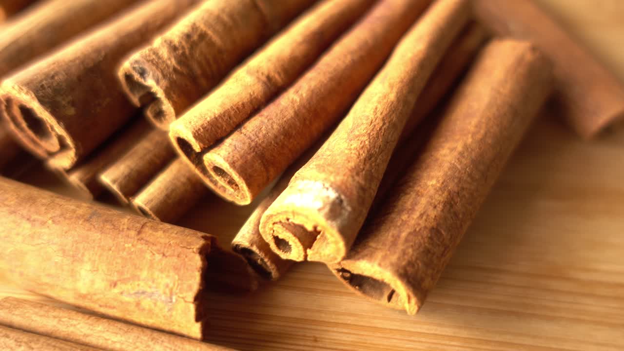 Paus de canela girando ao fundo, com um close-up de especiarias