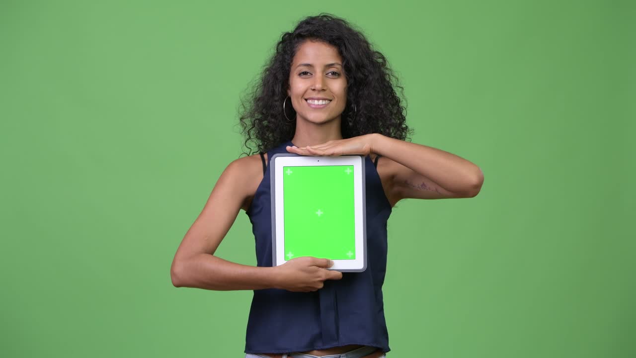 Ung, smuk latinamerikansk forretningskvinde viser digital tablet.