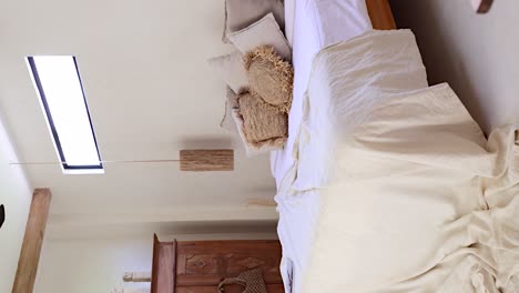 vertical - person's pov entering bohemian bedroom villa through a doorway revealing a made-up bed and exotic timber balinese decor