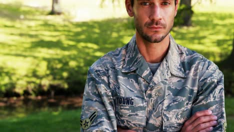 portrait of soldier standing with arms crossed in park