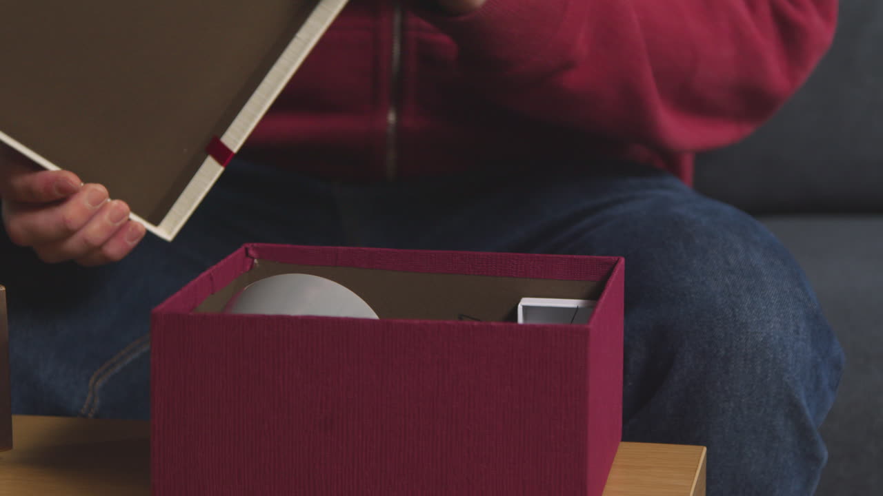 primer plano de un hombre abriendo un regalo envuelto en una caja de la mesa en el salón en casa