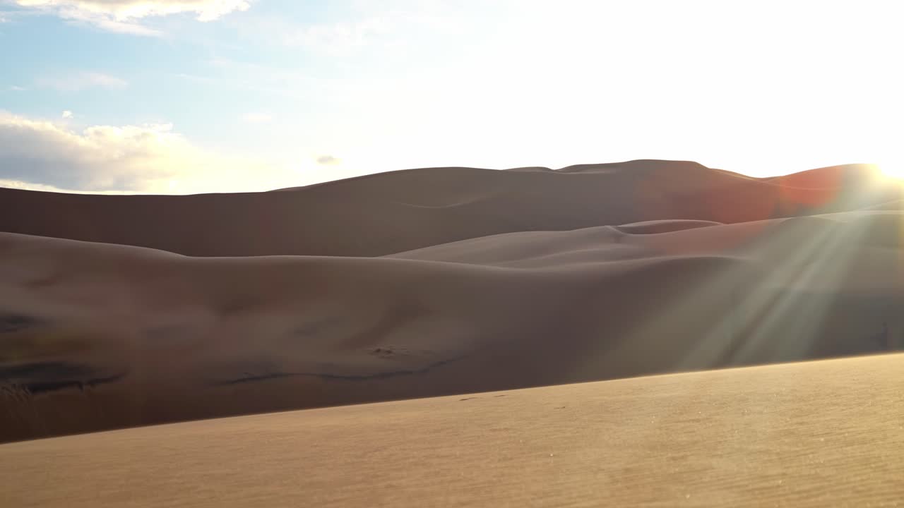 Warm evening light casts long shadows on smooth sand ridges in Great Sand Dunes National Park, natural backdrop background, no people