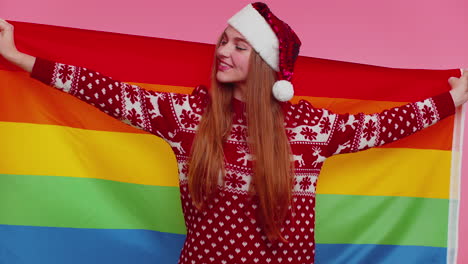chica con suéter de navidad posando con bandera del arco iris celebrando el desfile tolerancia matrimonios entre personas del mismo sexo