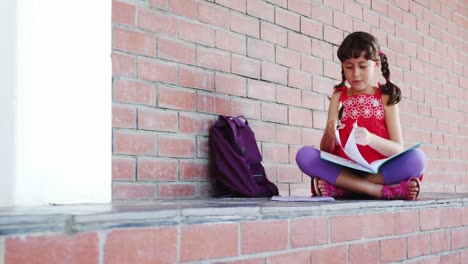 school girl sitting in corridor and doing homework at school