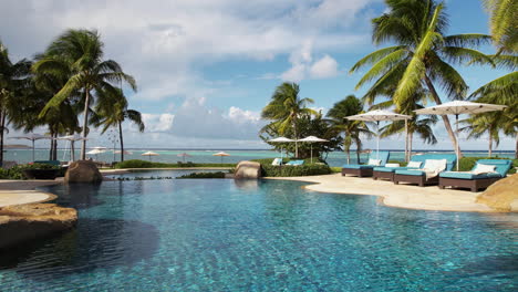 luxury tropical resort, swimming pools and palm trees on beachfront, drone shot