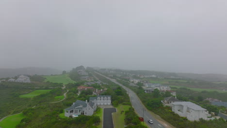 Vuela-Sobre-El-Distrito-Urbano-Residencial-De-Lujo-En-Las-Afueras-De-La-Ciudad.-Casas-A-Lo-Largo-De-La-Carretera-Rodeada-De-Vegetación-Verde.-Puerto-Elisabeth,-Sudáfrica