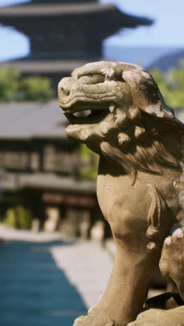 a stone lion statue in front of a japanese temple