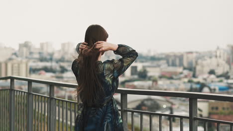 Una-Dama-Elegante-Ajusta-El-Cabello-Ondulado-En-El-Mirador-De-La-Ciudad