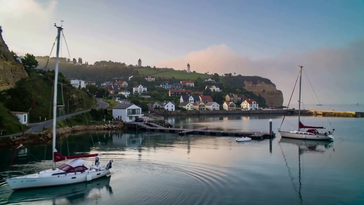 Draaiende zeilboot drijft weg van de pier in een kalme haven, maakt rimpelingen door een zacht briesje.