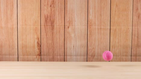una pelota de tenis rosa rebotando en una superficie de madera