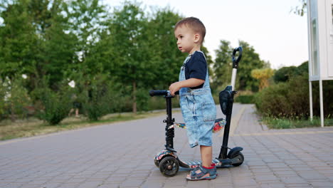 toddler boy riding scooter in park