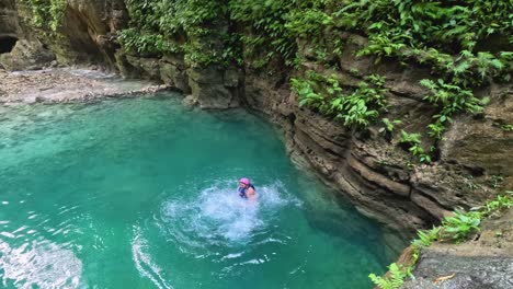 a man cliff jumps from a platform while canyoneering at kawasan falls in cebu, philippines