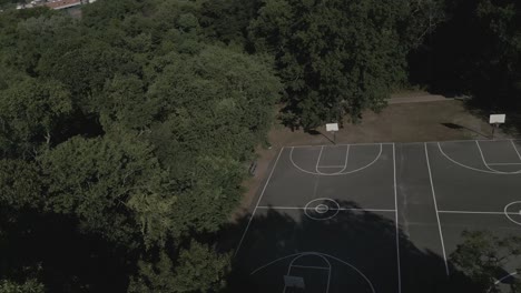 an aerial view of an empty black and white basketball court in a park on a beautiful day