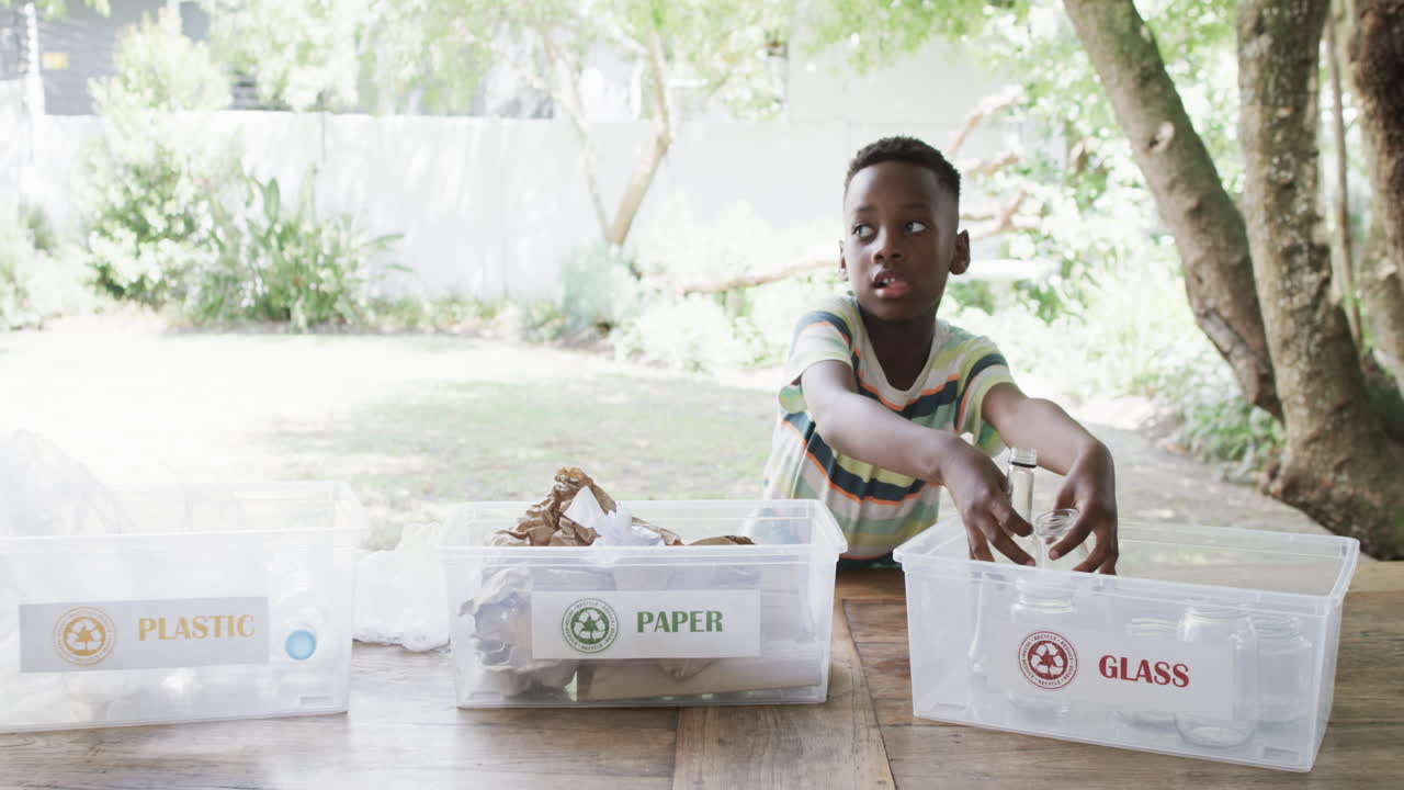 African American boy sorts recycling materials outdoor, with copy space
