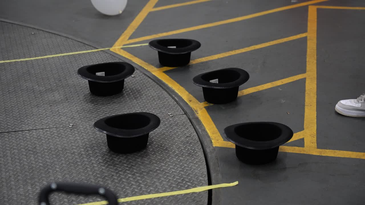 Close up of people thowing toy bunny rabbits into magician hats upside down and missing but bouncing in slow motion on the floor