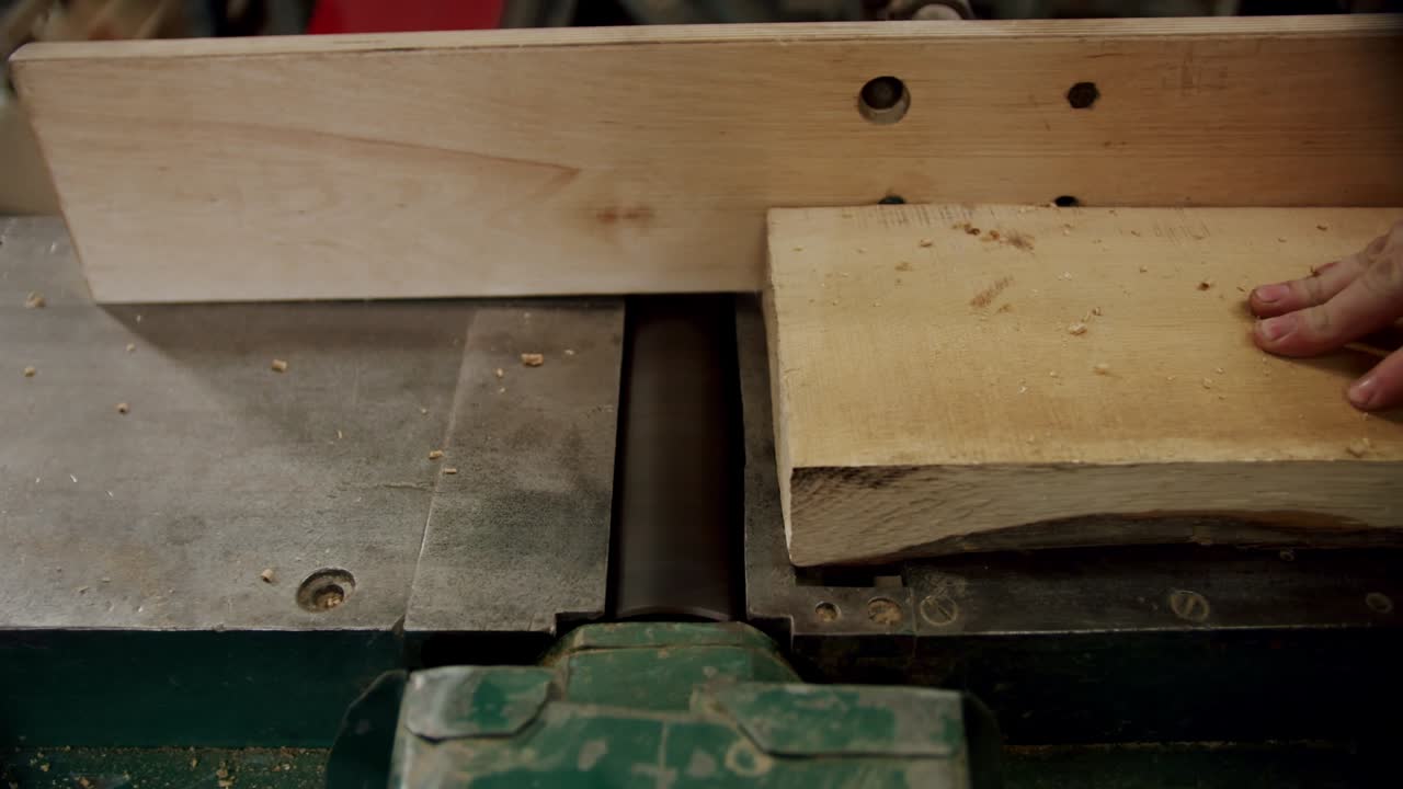 trabajador en un taller de carpintería, toma una tabla y la pone en una máquina en el taller decarpintería de un pequeño fabricante de muebles. vista superior