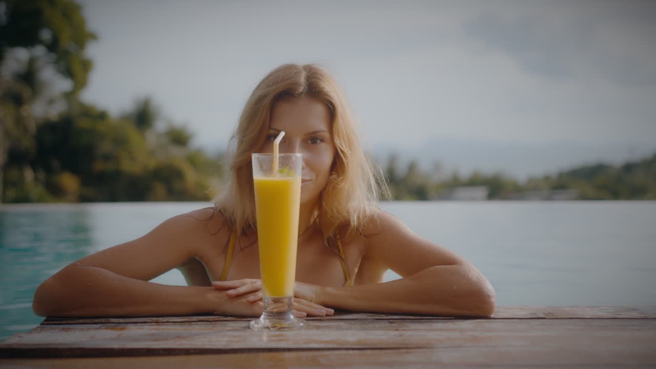 Kvinne nyter en smoothie ved bassenget