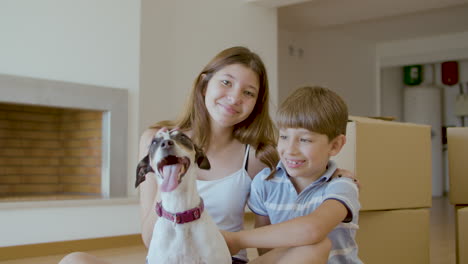 Glückliche-Kinder,-Die-Zu-Hause-Auf-Dem-Boden-Sitzen-Und-Den-Hund-Streicheln