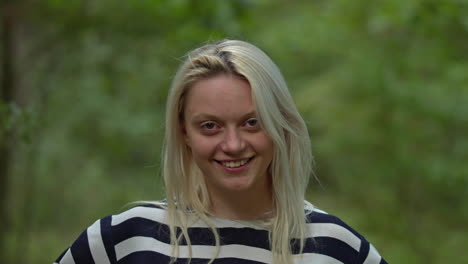 Portrait-of-happy-smiling-optimistic-blond-woman-looking-to-camera-in-a-summer-park-or-forest