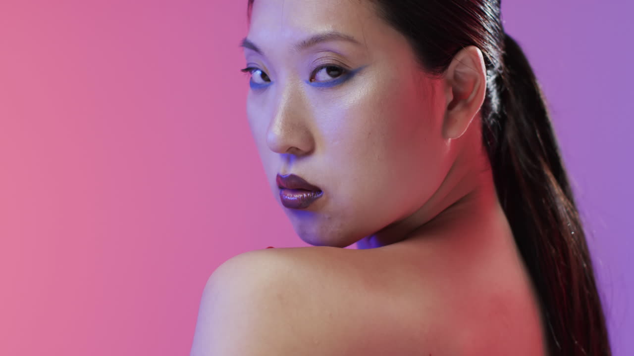 검은 머리카락과 메이크업을 가진 아시아 여성이 카메라를 보고, 공간을 복사, 느린 동작