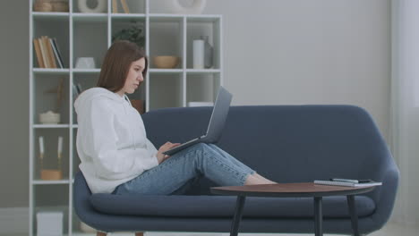 Vista-De-ángulo-Bajo-De-Una-Mujer-Sentada-En-Un-Sofá-Mirando-Su-Computadora-Portátil.-Carrera-Independiente.-Señora-Alegre-Trabajando-En-Una-Computadora-Portátil-Sentada-En-Un-Sofá-En-Casa.