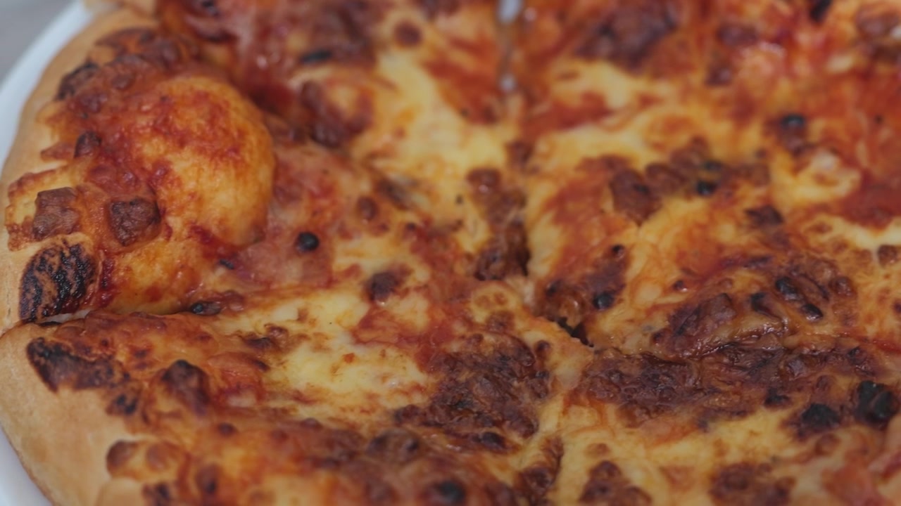 Primo piano di pizza al formaggio appena sfornata con formaggio fuso dorato e bollente, crosta croccante e una consistenza calda e invitante