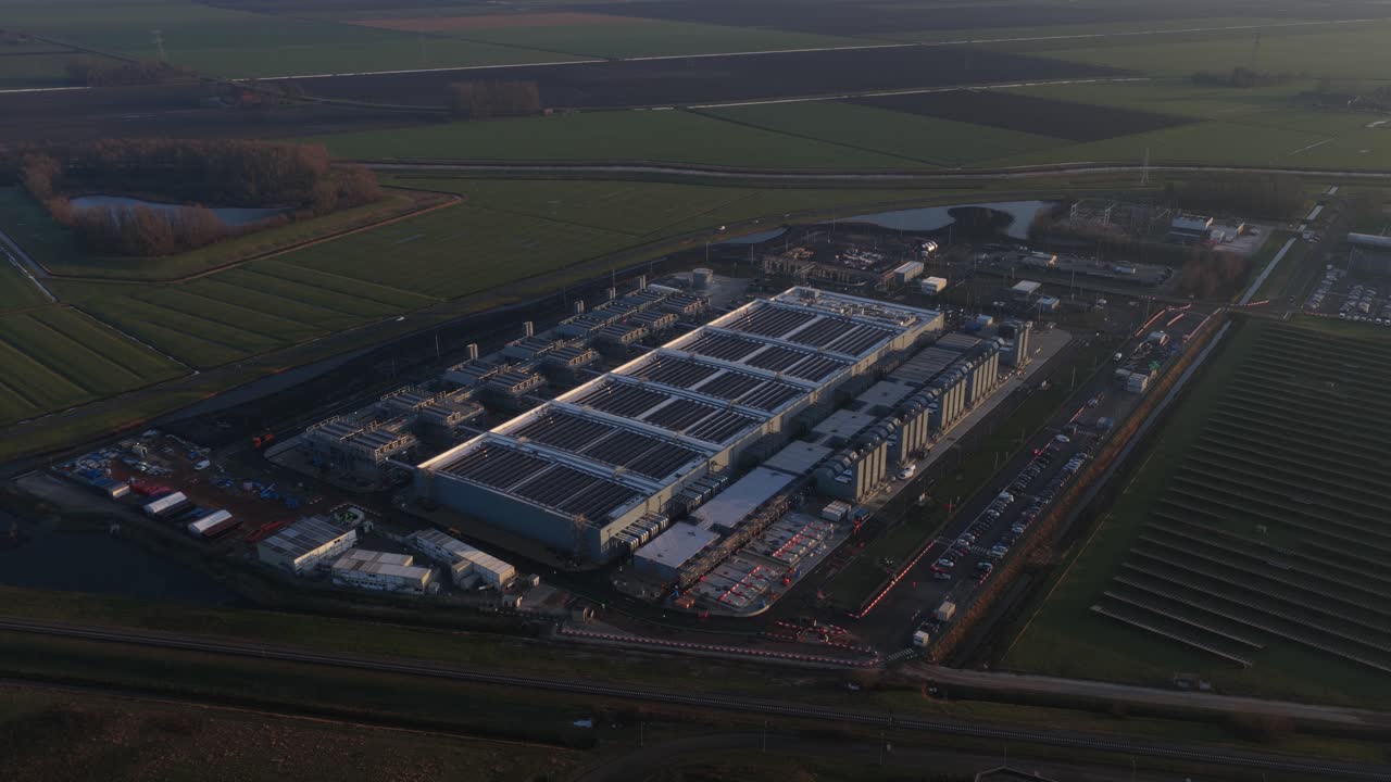 Dronevideo fra luften af et stort datacenter i Winschoten, Holland, der fremhæver big data-behandlingskraft, infrastruktur for kunstig intelligens, cloud computing-operationer og højt energiforbrug.