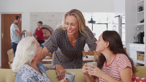 grandmother sitting on sofa talking with teenage granddaughter are joined by mother