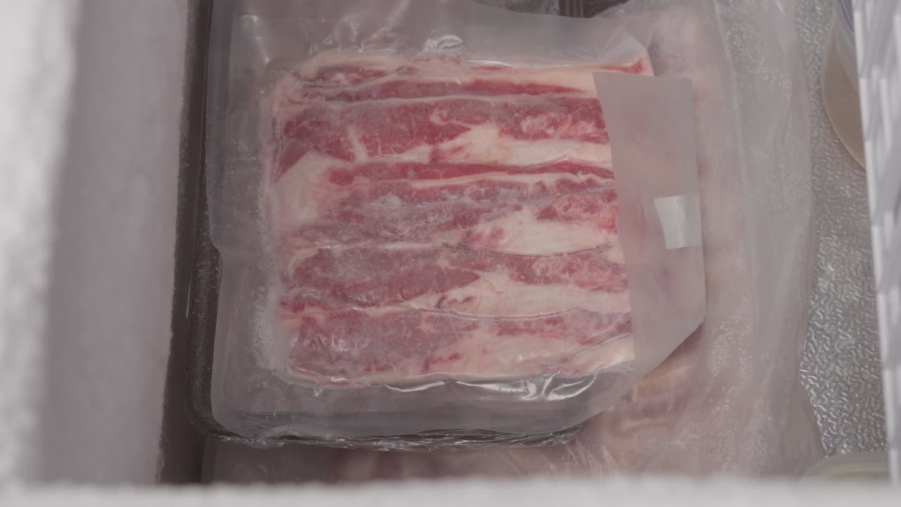 persona que saca un paquete de carne congelada del congelador