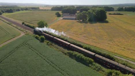 aerial view of a steam engine locomotive train passing on tracks in the countryside in england