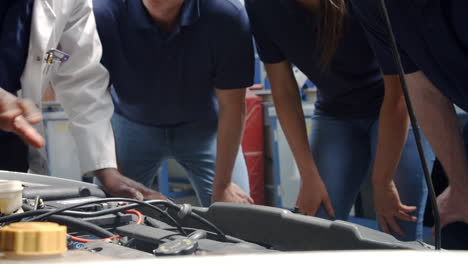 tutor explaining how engine works to group of apprentices