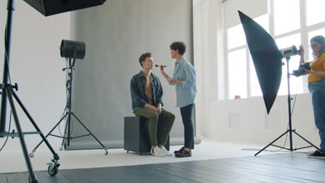 artista de maquillaje aplicando maquillaje a un modelo en un estudio fotográfico