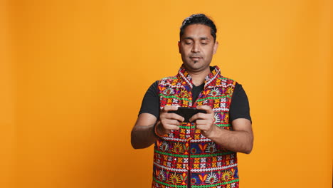 hombre jugando a videojuegos en el teléfono móvil en modo paisaje, fondo de estudio