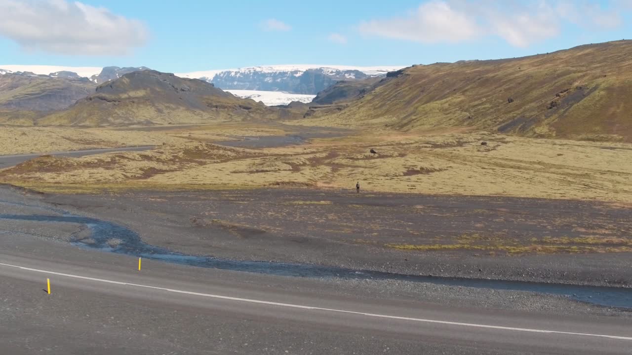 Person walking, Myrdalsjokull Glacier in background. Aerial flying backwards
