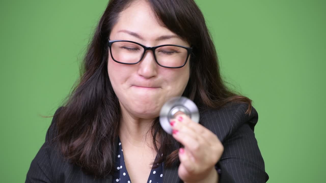 una hermosa mujer de negocios asiática madura jugando con fidget spinner.