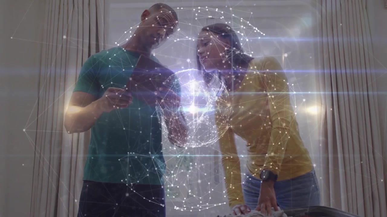 Coppia che tocca lo smartphone e proietta un ologramma tecnologico di un globo mentre sistema i vestiti nella valigia.