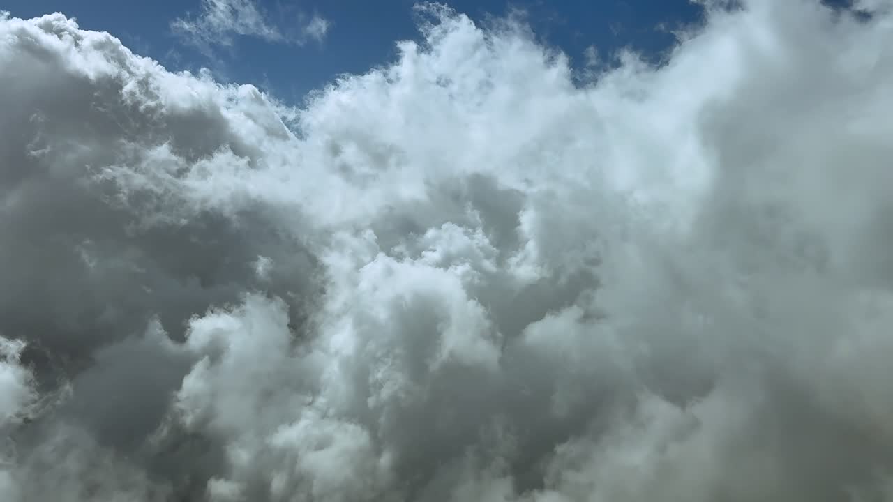 Immersive flight experience through the pilot’s eyes from the cockpit of a jet airplane flying through broken ethereal clouds in a blue sky. Ultra-realiustic 4K shot