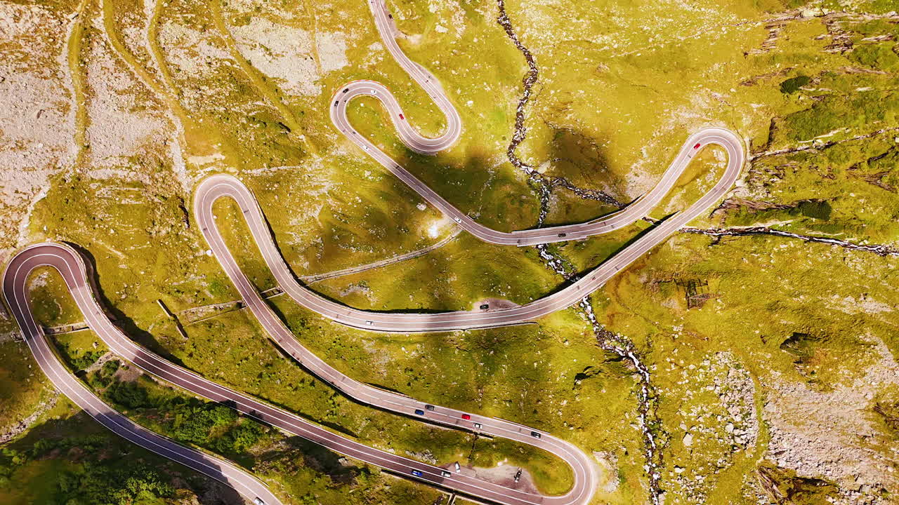 Winding serpentine road of Transfagarasan cutting through green slopes. The legendary Transfagarasan highway curves across the Romanian mountains