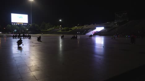 Silhouette-Of-People-Enjoying-Fun-Rides-At-Night-At-The-Lam-Vien-Square,-Illuminated-By-Large-LED-Screen-In-Dalat-City,-Vietnam