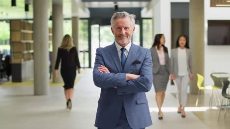 portrait of senior businessman ceo chairman standing in lobby of busy modern office building