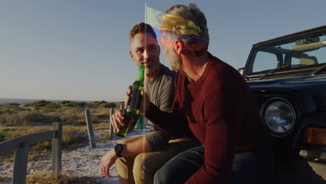 sitting on vehicle by beach, two men drinking and relaxing together