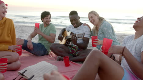 Verschiedene-Freunde-Genießen-Ein-Strandtreffen-Bei-Sonnenuntergang