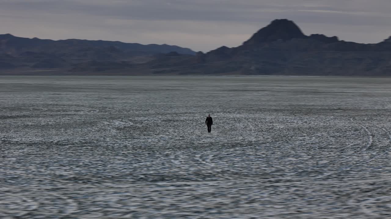 Orbiting Drone Shot of Lonely Man Walking in Desert Landscape. Bonneville Salt Flats, Utah USA
