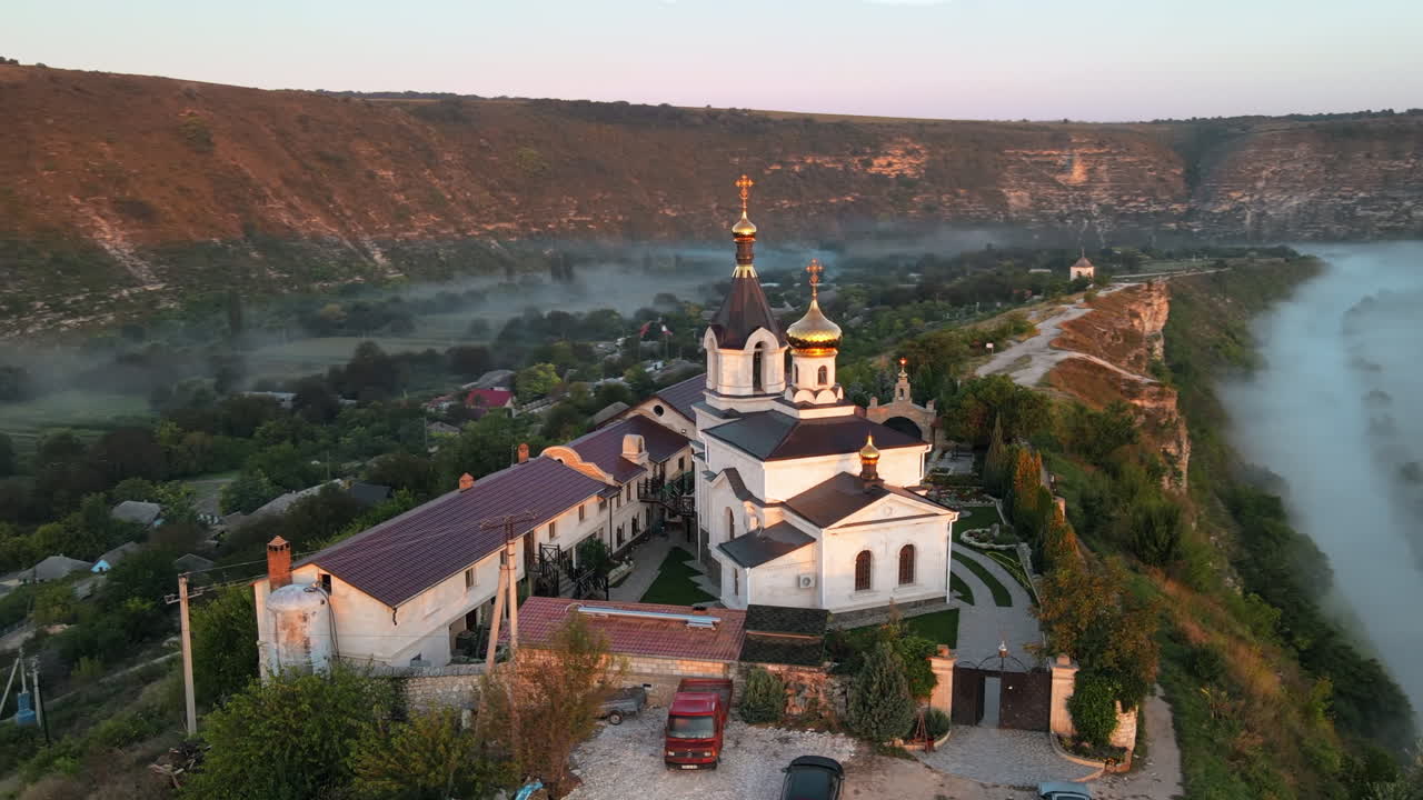 Aerial drone view of the Old Orhei at sunset. Valley with river and fog, village, monastery located on a hill in Moldova