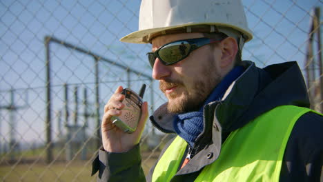 Male-engineer-listening-to-the-radio-while-nodding-his-head-and-puts-it-down,-handheld-closeup